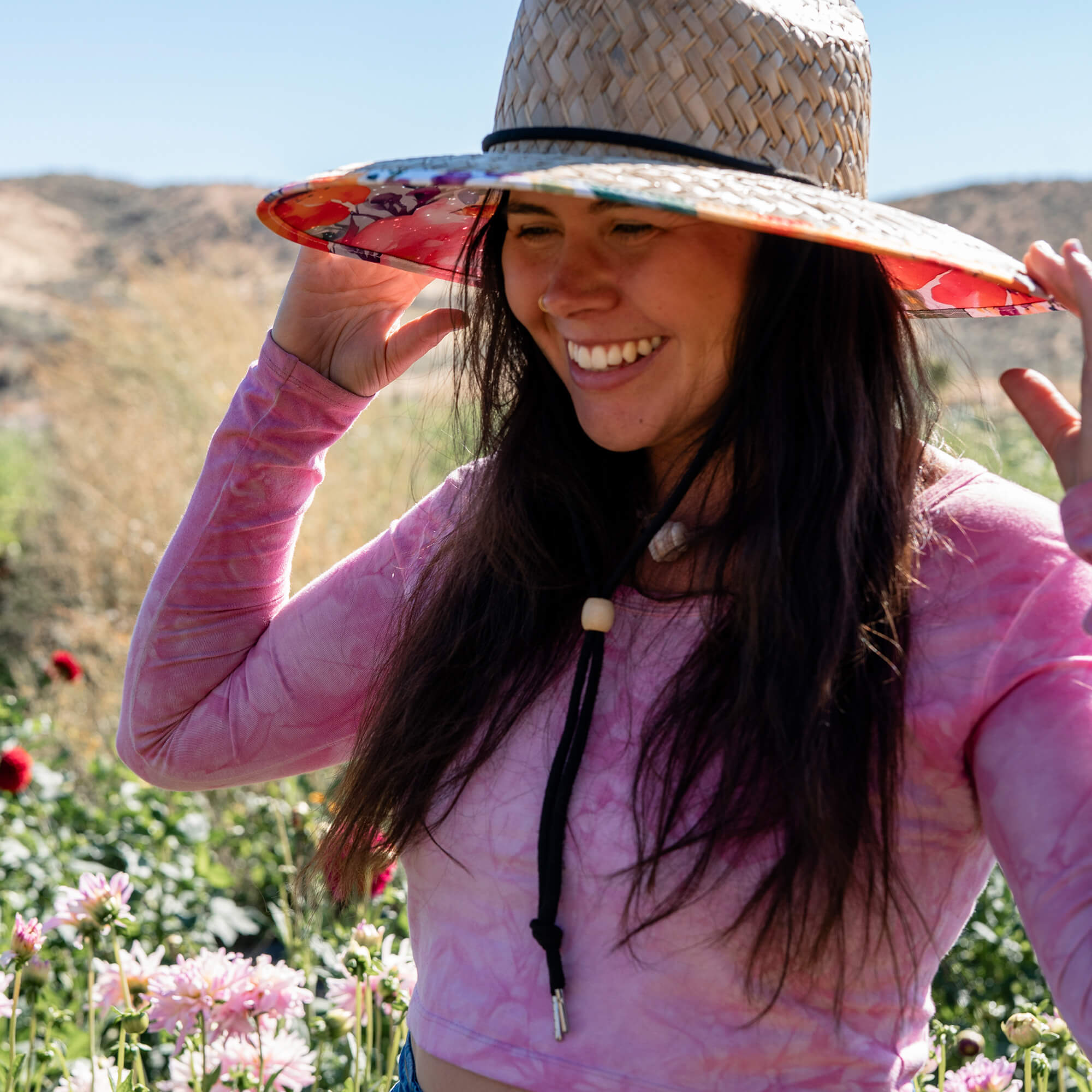 Woman wearing a Charlee Girl wide brim straw sun hat outdoors in warm natural light