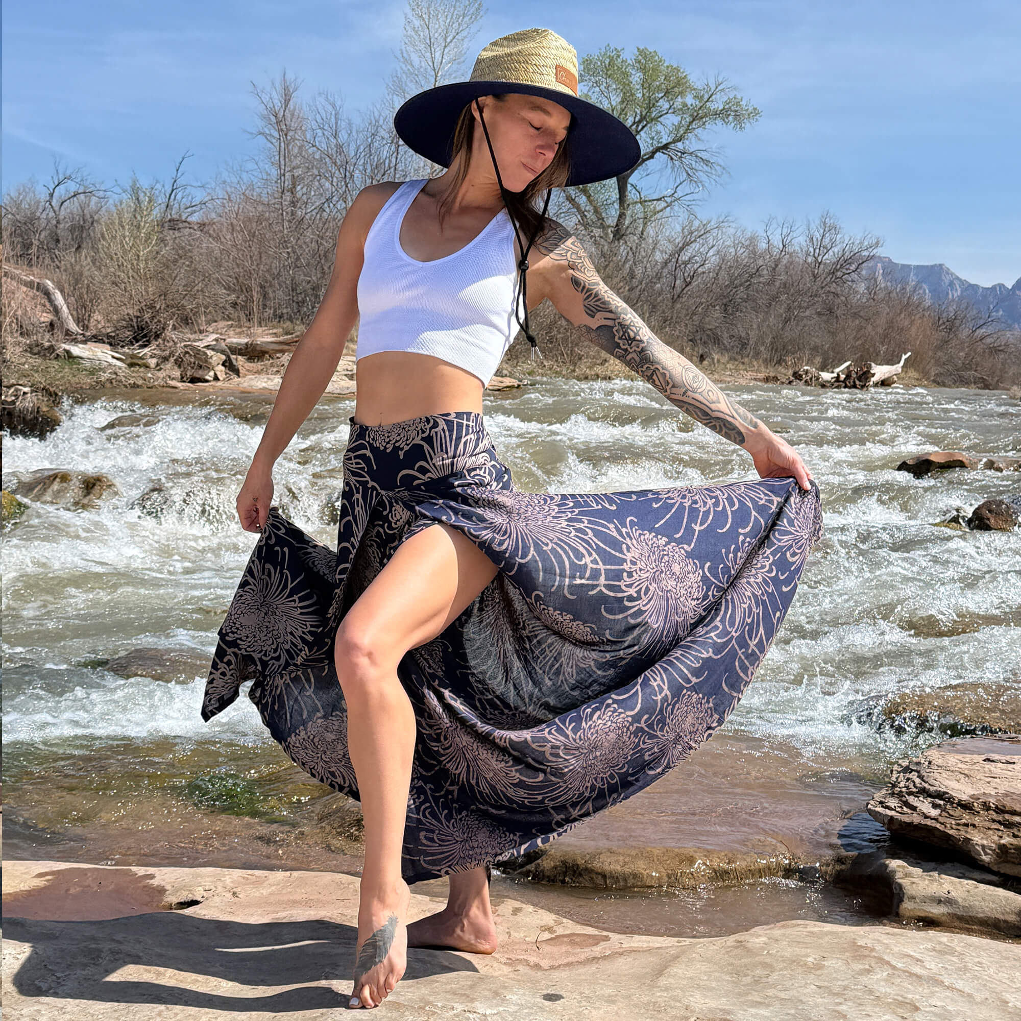 Woman wearing flowy wide leg palazzo pants with a fitted top and straw hat outdoors