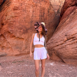 Karlene wearing The Anna Hollow Mat straw sun hat with white shorts — lifeguard style boho sun hat