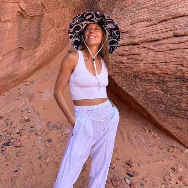 Karlene wearing The Ashley Hollow Mat straw hat with white harem pants — lifeguard brim boho sun hat