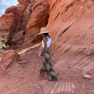 Karlene in Wild Bloom Rooted Earth palazzo pants with straw hat — brown floral palazzo pants